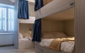 a bedroom with a bunk bed with blue curtains at The Rose Hostel in St. Julianʼs