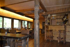 ein Esszimmer mit Holzwänden, Tischen und Fenstern in der Unterkunft 4 Mountains Hotel in Bystrets