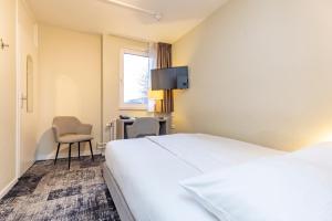 a hotel room with a bed and a desk and a tv at Fletcher Hotel Valkenburg in Valkenburg