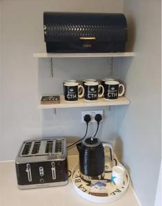 a counter with a toaster and coffee cups on a shelf at The Courtyard - Cosy, secluded with luxury suite in Walmer