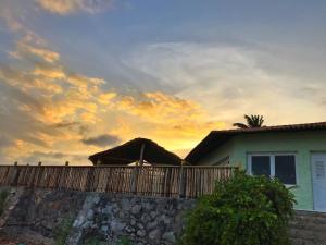 a house with a fence in front of a sunset at Paraíso das Canárias in Araioses