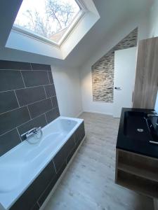een badkamer met een bad en een wastafel bij Vlakbij het centrum genieten van de rust. in La-Roche-en-Ardenne