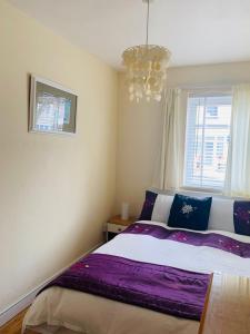 um quarto com uma cama com lençóis roxos e um lustre em Towan Beach Holiday Flat em Newquay