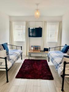 sala de estar con 2 camas y alfombra roja en Towan Beach Holiday Flat en Newquay