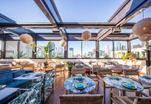 un restaurante con mesas, sillas y ventanas grandes en The Hoxton, Downtown LA en Los Ángeles