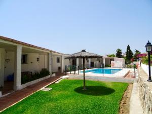 una casa con un cortile con piscina e ombrellone di RIVIERA PLAYA 200m to the beach in Riviera del Sol, Mijas Costa a Sitio de Calahonda