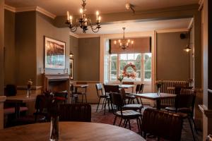 a restaurant with tables and chairs and a chandelier at The Falcon Inn in Painswick