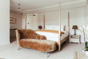 a bedroom with a canopy bed and a chair at The Falcon Inn in Painswick