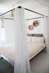 1 cama con cortinas blancas en un dormitorio en Lazy Daze en Hastings