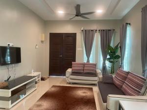 a living room with a couch and a flat screen tv at VISTANA INDAH HOMESTAY in Alor Setar