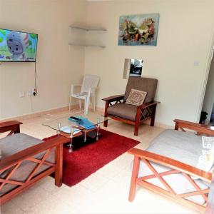 uma sala de estar com mobiliário em madeira e um tapete vermelho em Twende Nanyuki Homes em Nanyuki