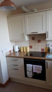a kitchen with white cabinets and a stove top oven at Modern 1 bed Apartment close to Campbeltown in Campbeltown