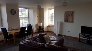 a living room with a couch and a table and a television at Modern 1 bed Apartment close to Campbeltown in Campbeltown