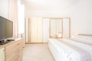 a white bedroom with a bed and a flat screen tv at Apartman Ivano in Pula