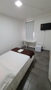 a white bedroom with a bed and a tv at BeB Hotel in Macapá