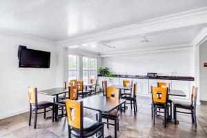 a dining room with tables and chairs and a tv at OYO Hotel Baton Rouge East I-12 Louisiana in Baton Rouge