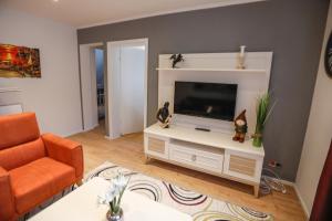 uma sala de estar com uma televisão e uma cadeira laranja em Turis Ferienwohnung 65-3 em Triberg