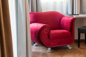 una silla roja sentada junto a una ventana en Hotel Schlosswirt, en Scena