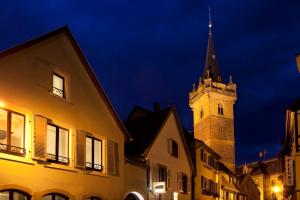 un bâtiment avec une tour d'horloge la nuit dans l'établissement Hotel Le Pavillon 7, à Obernai