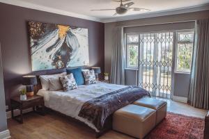 a bedroom with a bed and a painting on the wall at Kingsbeach Cottages in Port Elizabeth