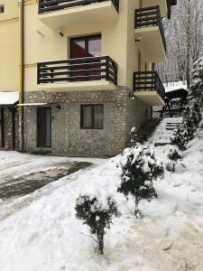 a house with snow in front of it at Apartament Nicolle in Poiana Brasov