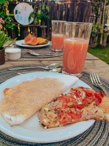 a plate with a slice of pizza and a glass of juice at Pousada Jaboticaba Caraíva in Caraíva