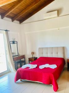 a bedroom with a red bed with a red blanket at Villa Oniro Kreta in Kalamaki Heraklion