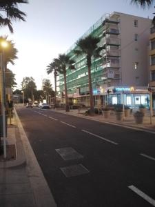an empty street with palm trees and a building at Appartement Ipanema Sud in Canet-en-Roussillon