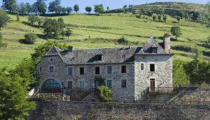 a large stone house sitting on top of a hill at B&B Manoir de la Fabrègues in Estaing