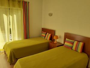 two yellow beds in a room with a window at Clube Meia Praia in Lagos