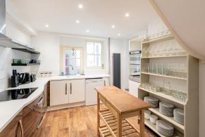 a kitchen with white cabinets and a wooden table at Historic country house retreat with indoor swimming pool and hot tub, ideal for large groups in Petty France