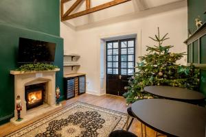 un salon avec un sapin de Noël, des tables et une cheminée dans l'établissement Cotswold Spa House - Country house retreat with indoor swimming pool and hot tub, ideal for large groups, à Petty France