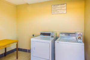 a laundry room with a washer and dryer next to a table at OYO Hotel Brookhaven MS - I-55 in Brookhaven