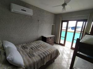 a bedroom with a bed and a window with a balcony at Hostel Dunas in Florianópolis