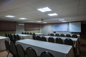 a conference room with tables and chairs and a screen at Hotel Marina in Antofagasta