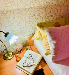 a table with a book and glasses on a bed at Hotel Penzion Trámky in Vikýřovice