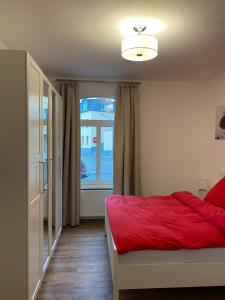 a bedroom with a red bed and a window at Schwartz GmbH in Greiz