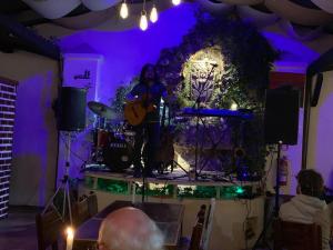 a woman playing guitar on a stage in a purple room at Hostal Yakumama in Cuenca