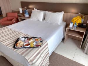 bandeja de comida en una cama en una habitación de hotel en Athos Bulcão Hplus Executive, en Brasilia