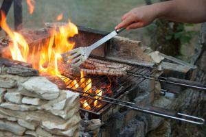 a person cooking sausages on a grill with a fork at Le Bois de Faral in Le Bastit