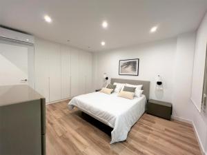 Habitación blanca con cama blanca y suelo de madera. en MARINA SUNBEACH SEA VIEW, en Torrevieja