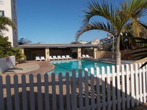 a white fence next to a swimming pool with a palm tree at 104 Santana Resort, Margate Beach in Margate +15 photos