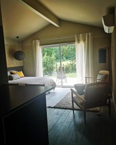 sypialnia z łóżkiem, krzesłem i oknem w obiekcie Cabane chic et romantique MERLOT près de Bordeaux w mieście Saint-Sulpice-et-Cameyrac