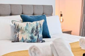 ein weißes Bett mit einem blauen Kissen darauf in der Unterkunft 4-Bed - 2 Bath - Off-Road parking - Ideal for Contractors in Swansea