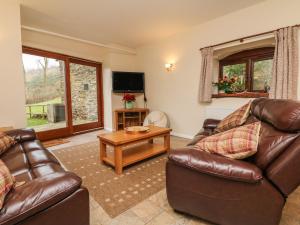 a living room with two leather couches and a tv at Red Deer Cottage in Minehead