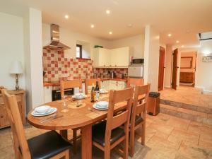 a kitchen and dining room with a wooden table and chairs at Red Deer Cottage in Minehead