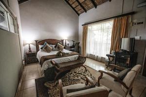 a bedroom with a bed and chairs and a television at Selati 103 Guest Cottages in Malelane