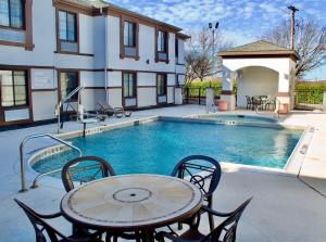 a pool with a table and chairs next to a building at Quality Inn & Suites Irving DFW Airport South in Irving