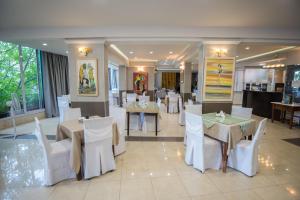 a restaurant with white tables and white chairs at Hotel Pegasos in Nikiana