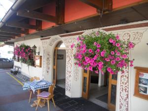 a building with a table and flowers hanging from it at Hotel Alpenblick in Klosters
